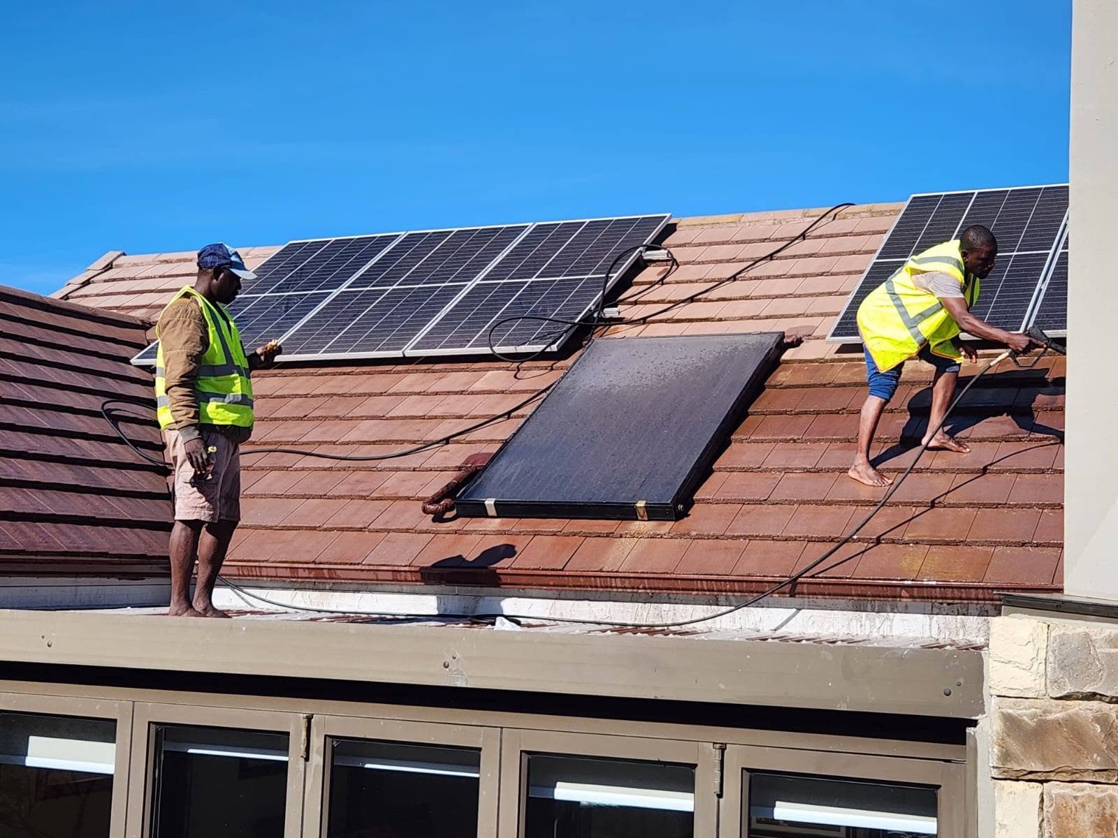 Rows of solar panels being cleaned in sunlight